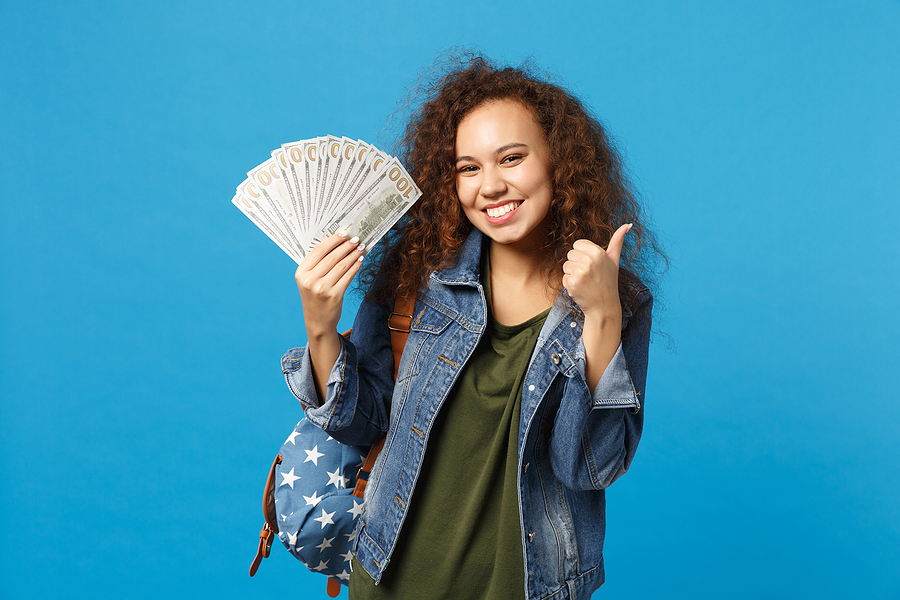 student in denim clothes and backpack holding cash loans for teens